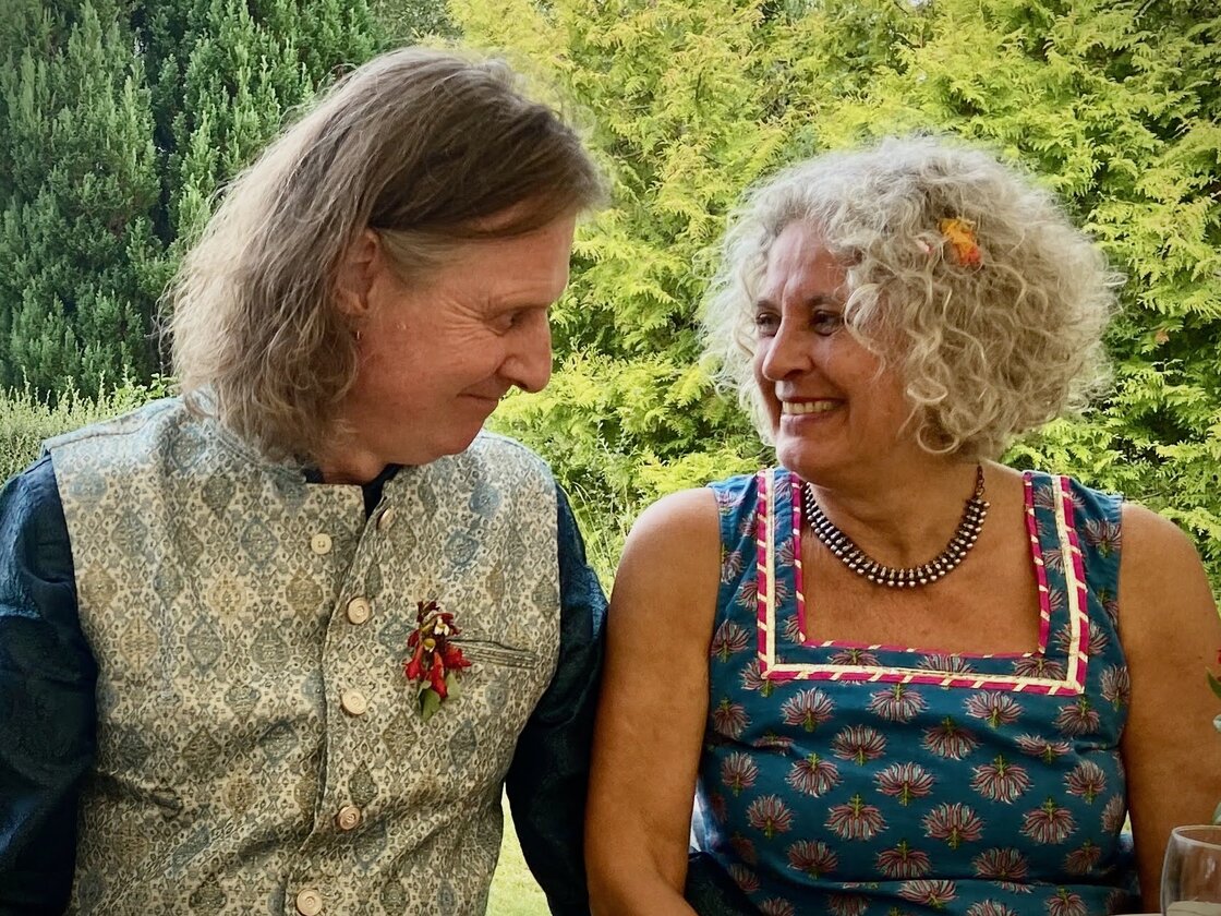 Peter and Kathy smiling at each other at a table in the garden